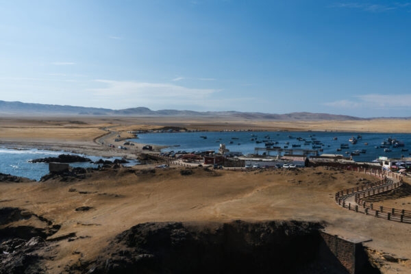 Playa Lagunillas Paracas - Vista de la tranquila Playa Lagunillas con su mar cristalino, embarcaciones y turistas disfrutando del paisaje en Paracas Ica.