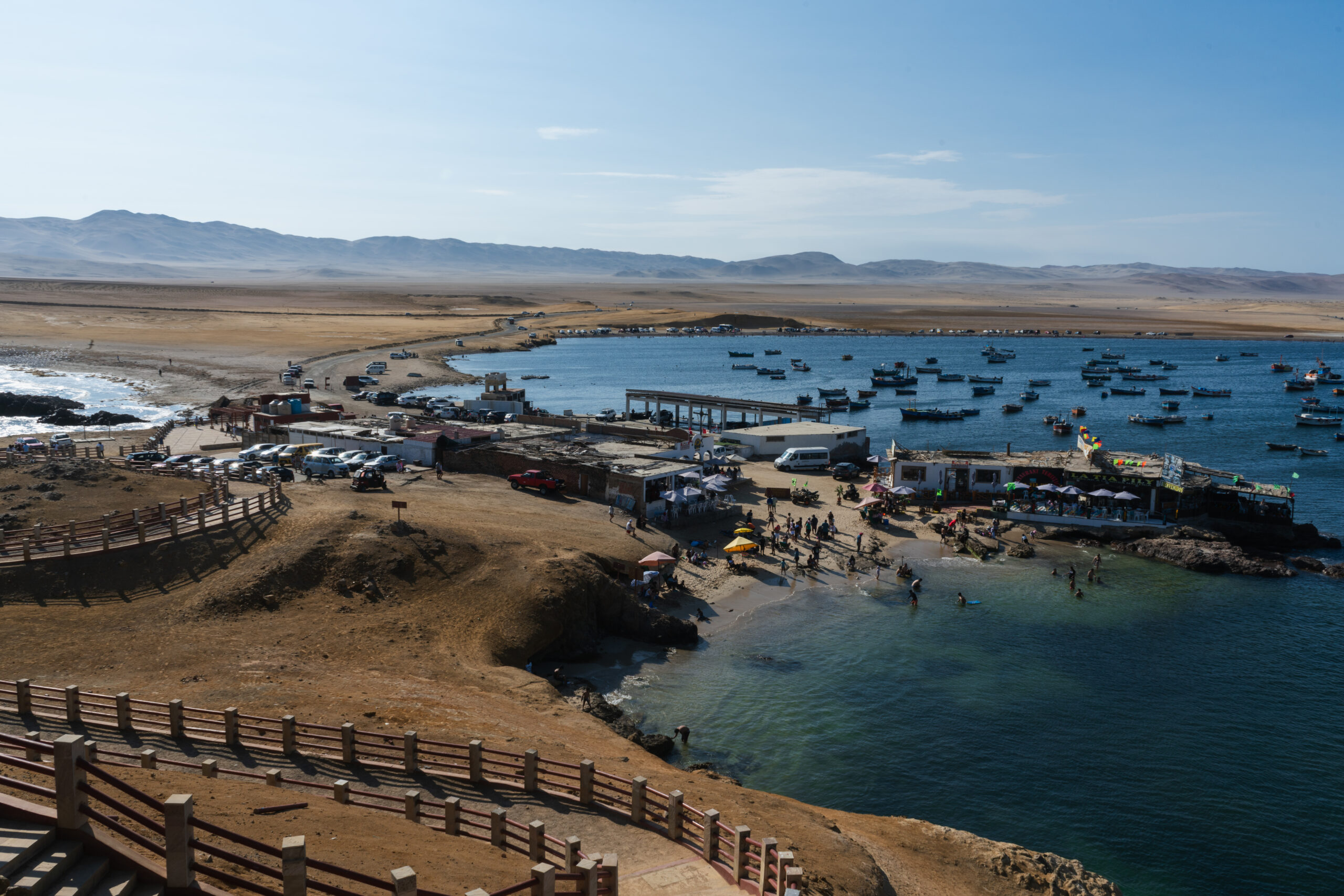 Playa Lagunillas Paracas - Vista de la tranquila Playa Lagunillas con su mar cristalino, embarcaciones y turistas disfrutando del paisaje en Paracas Ica.